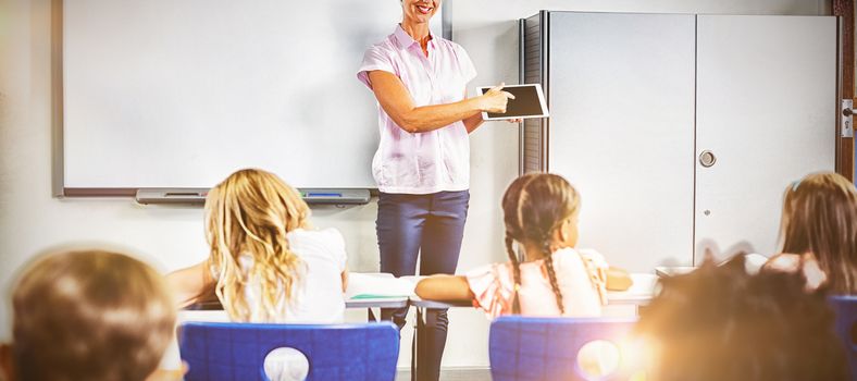 Teacher teaching kids on digital tablet in classroom at school