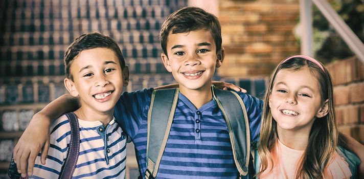 Portrait of smiling school kids standing with arm around at school