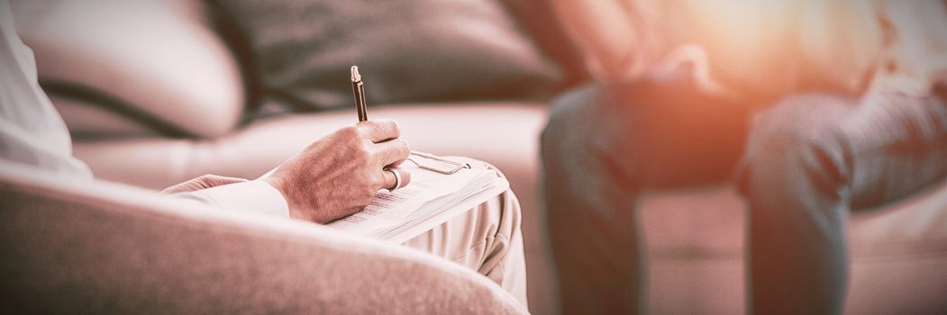 Therapist making notes of patient on sofa at home