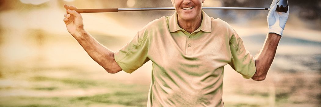 Portrait of smiling mature golfer carrying golf club while standing on field