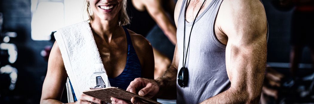 Portrait of smiling fitness instructor with woman standing in gym