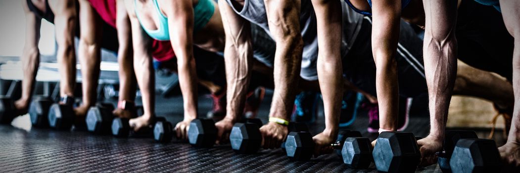 People doing push ups with dumbbell while exercising in gym