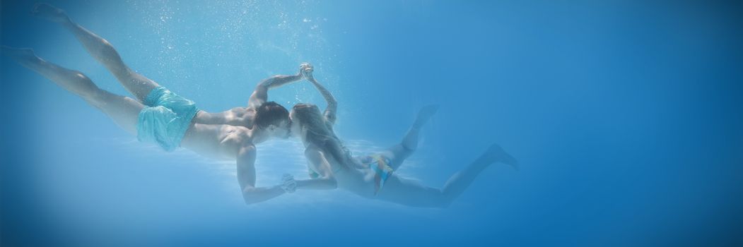 Cute couple holding hands underwater in the swimming pool on their holidays