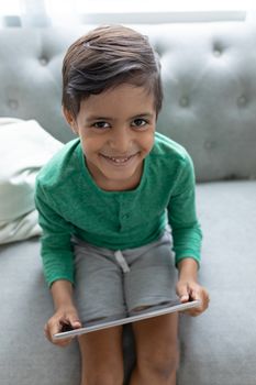 Portrait of African american boy using digital tablet on a sofa in living room