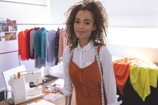 Portrait of female fashion designer standing at table in design studio