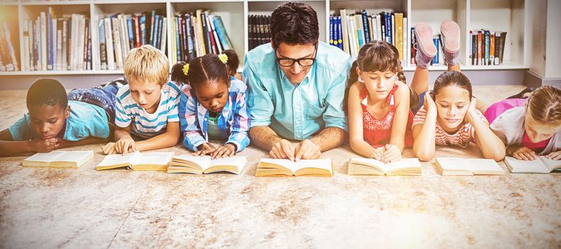 Teacher and kids lying on floor reading book in library