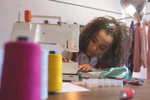 Front view of female fashion designer working with sewing machine