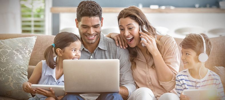 Parents and kids using laptop and digital tablet in living room at home