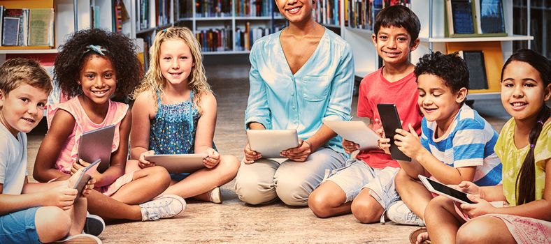 Portrait of female teacher with children holding digital tablets in library