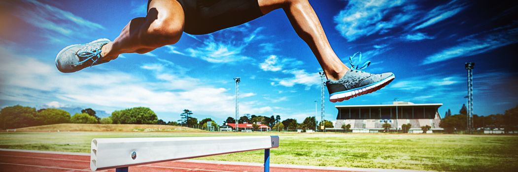 Female athlete jumping above the hurdle during the race