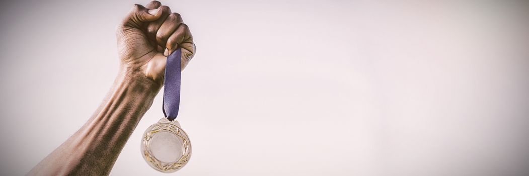 Athletes hand holding gold medal against sky, Close-up