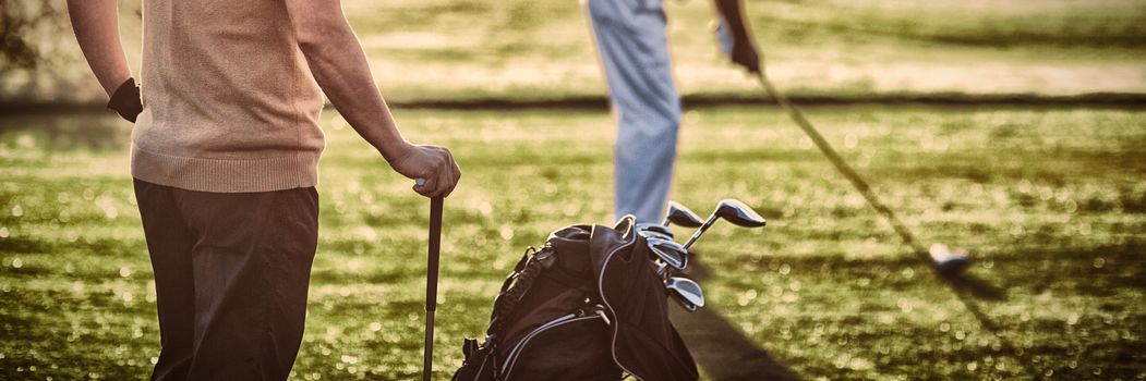 Mature golfer men standing on field during sunny day