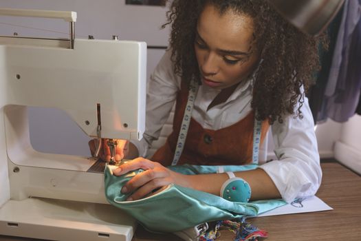 Front view of female fashion designer working with sewing machine
