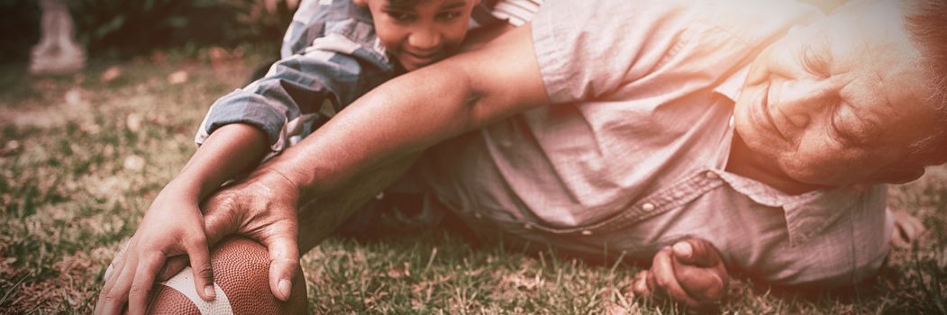 Happy family playing rugby ball on field in yard