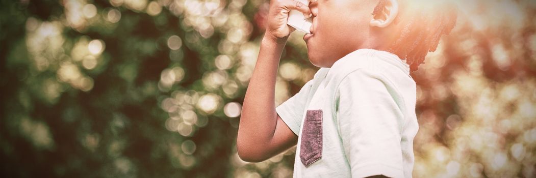 Boy using an asthma inhaler in the park