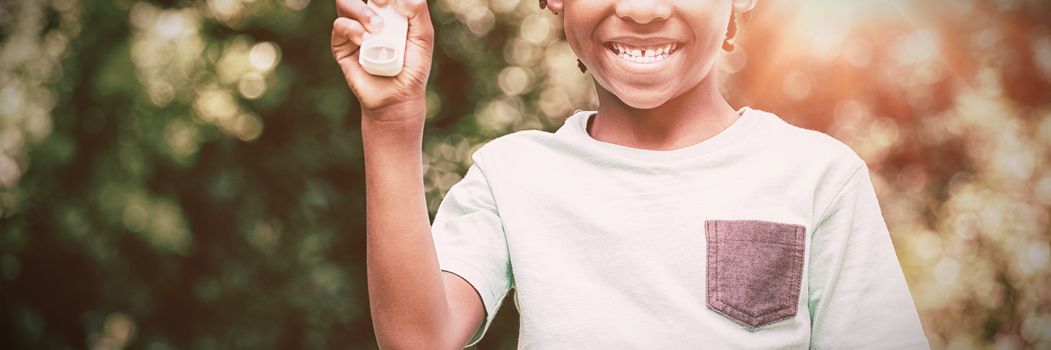 Boy showing his asthma inhaler in the park