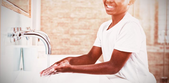 Portrait of smiling boy washing hands in sink at bathroom