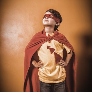 Boy dressed as a superhero on yellow background