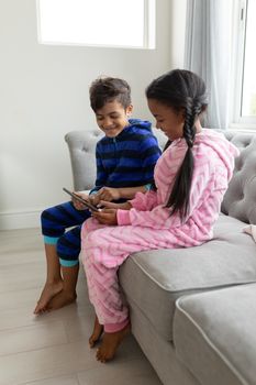 Side view of African american Happy Siblings using digital tablet on a sofa in living room at home