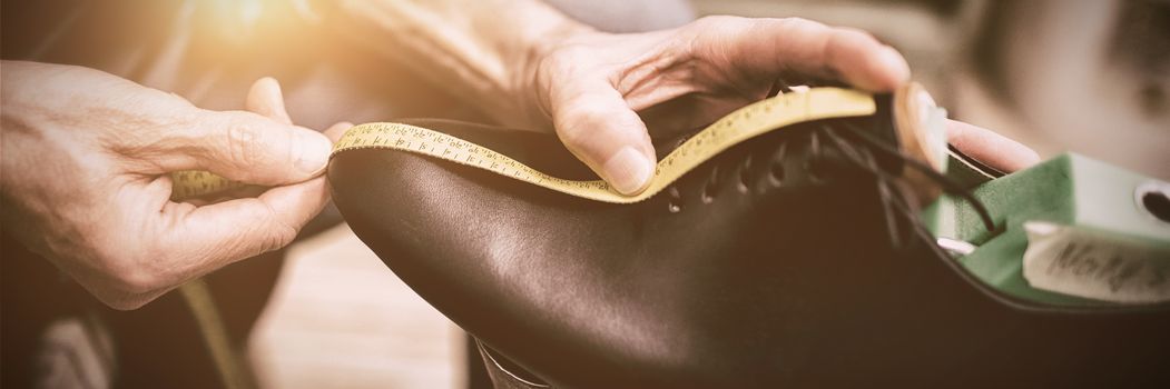 Close up of cobbler measuring a shoe with a tape