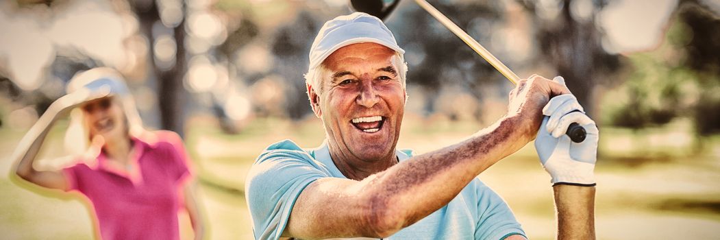 Portrait of happy mature golfer holding golf club while standing on field