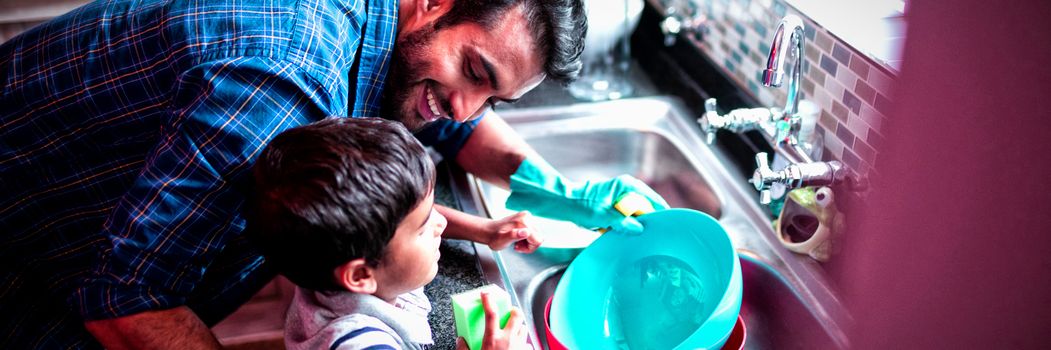 High angle view of father and son cleaning utensils at home