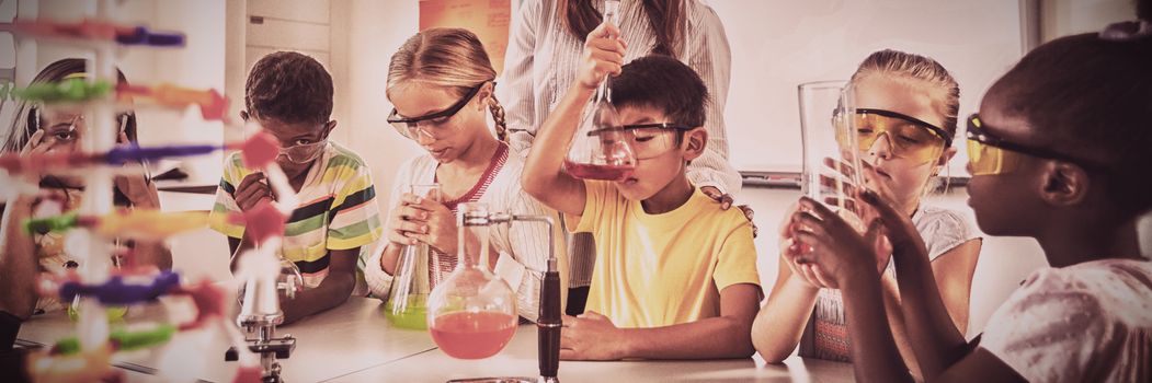 A teacher posing with pupils doing science project in classroom