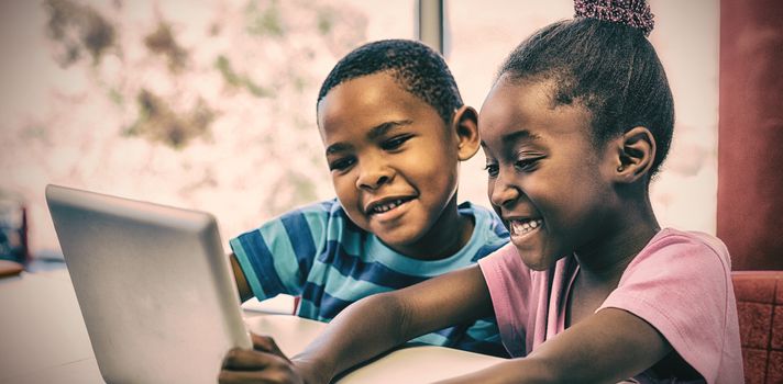 Smiling children using digital tablet in classroom at school