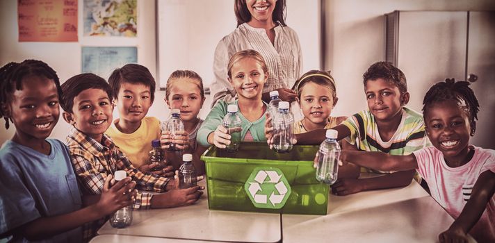 Portrait of pupils and teacher recycling in classroom
