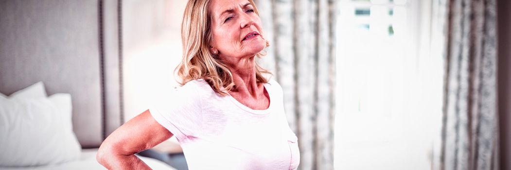 Senior woman having back pain in bedroom at home