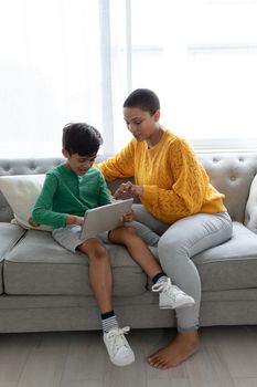 Front view of African american mother and son using digital tablet on a sofa in living room at home