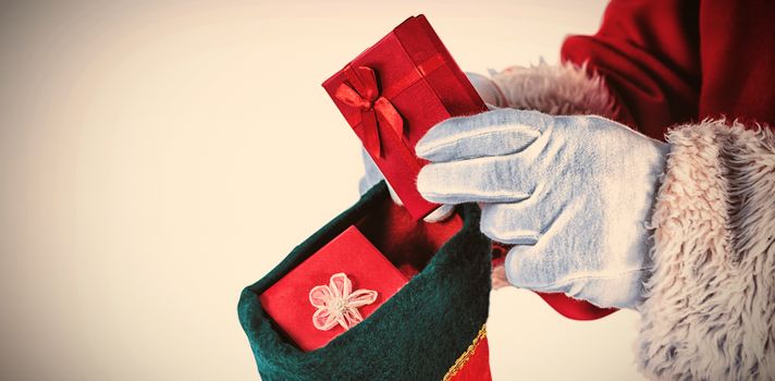 Close up of Santa Claus putting presents in Christmas stockings against white background