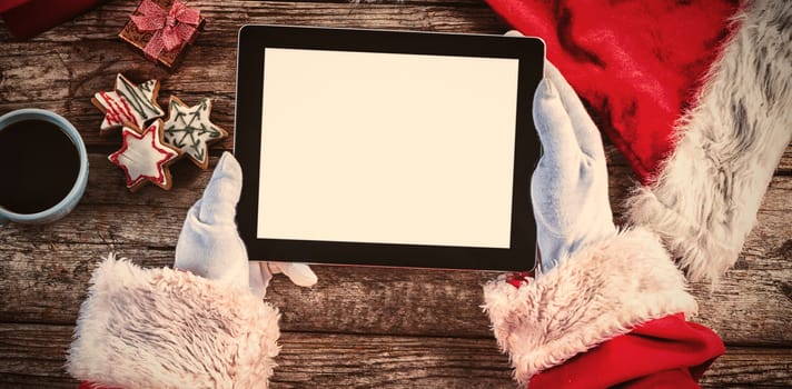 Cropped image of Santa Claus holding  digital tablet on wooden table