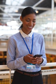 Portrait Close-up of happy young mixed race businesswoman leaning on railing and using mobile phone in a modern office. International diverse corporate business partnership concept