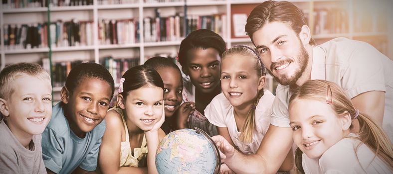 Pupils and teacher looking at globe in library at elementary school