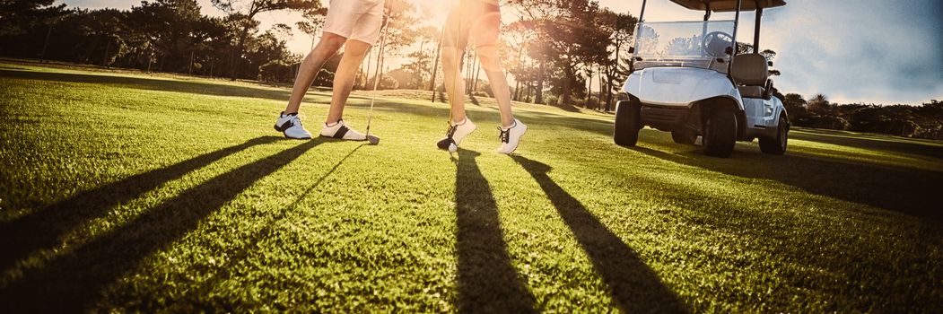 Happy golf player couple giving high five while standing on field