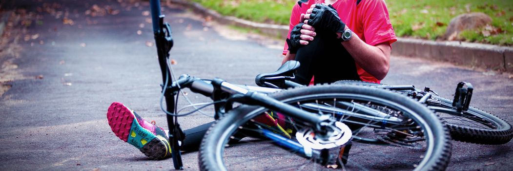 Male cyclist getting injured while falling from mountain bike in park