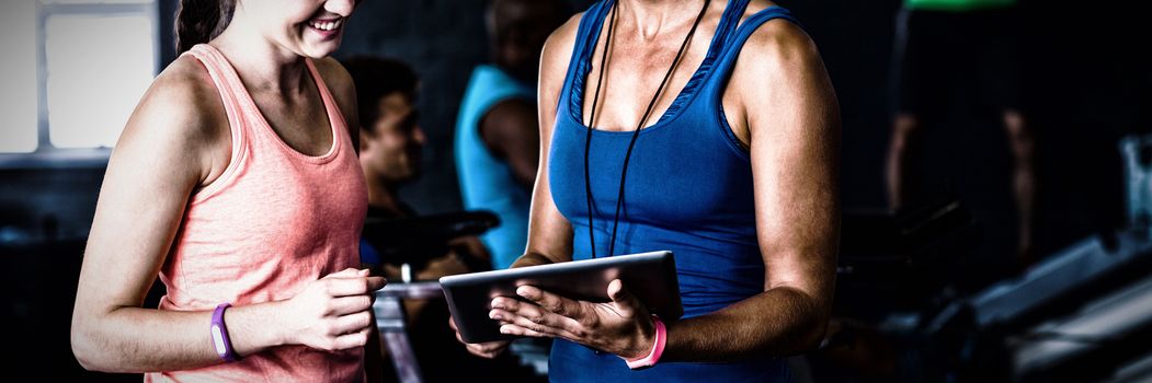 Smiling friends with digital tablet while standing in gym