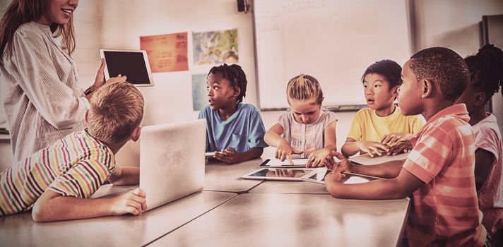 Teacher giving lesson with digital tablet to students in classroom