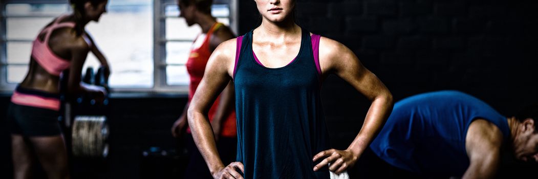 Portrait of fit woman with hands on hip while standing in gym