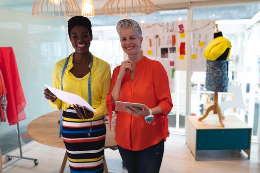 Portrait of diverse female fashion designers discussing over sketch design in design studio. This is a casual creative start-up business office for a diverse team