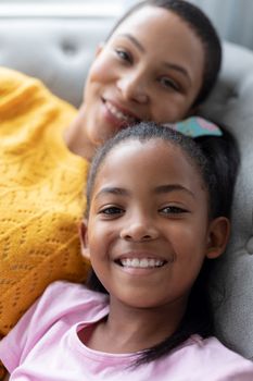 Portrait of African american Mother and daughter relaxing on a sofa in living room at home