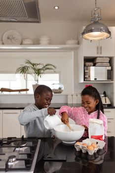 Front view of African american siblings preparing food on a worktop in kitchen at home