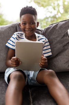 Portrait of African american boy using digital tablet in living room at home