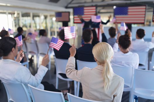 Front view of diverse Business people waving an American flag in business seminar. International diverse corporate business partnership concept