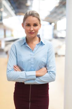 Portrait of Caucasian businesswoman standing with arms crossed in the corridor at office. International diverse corporate business partnership concept