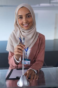 Close-up of mixed-race female speaker in hijab looking at camera while speaking in a business seminar. International diverse corporate business partnership concept