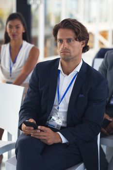 Close-up of caucasian businessman listening to speaker in a business seminar. International diverse corporate business partnership concept