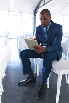 Front view of African-american Male speaker practicing his speech on digital tablet in business seminar at conference room. International diverse corporate business partnership concept