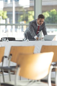 Front view of businessman watching his computer in empty conference room